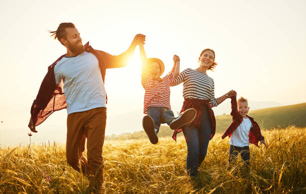 幸せな家族:太陽の下で母、父、子供の息子と娘 - child dancing ethnic outdoors ストックフォトと画像