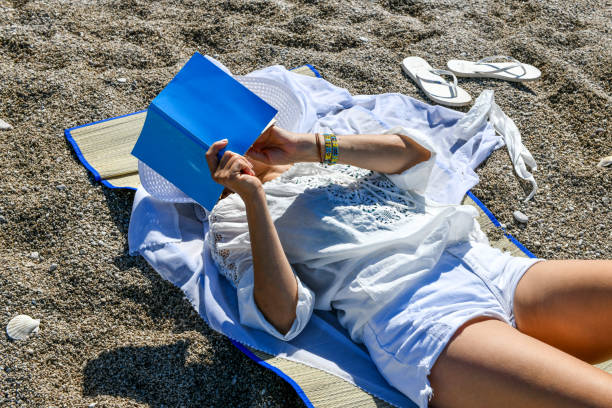 istock Woman studying book at the beach. 1156678316