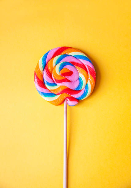 istock Colorful rainbow lollipop, yellow background, centered, vertical 1156678792