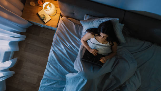 istock Top View Young Woman in Bed Working on a Laptop Computer at Night. Student Getting Ready to Exams, Exceptionally Dedicated Project Manager Finishing Work in Bed at Night. 1156679490