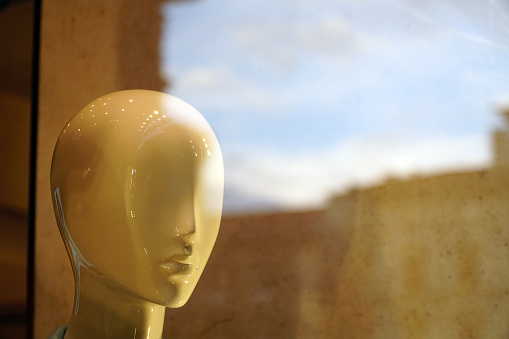 white head of shop dummy behind reflecting glass, looking to the right