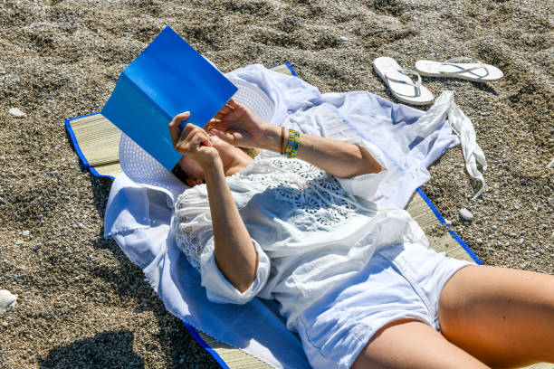 istock Woman studying book at the beach. 1156680244