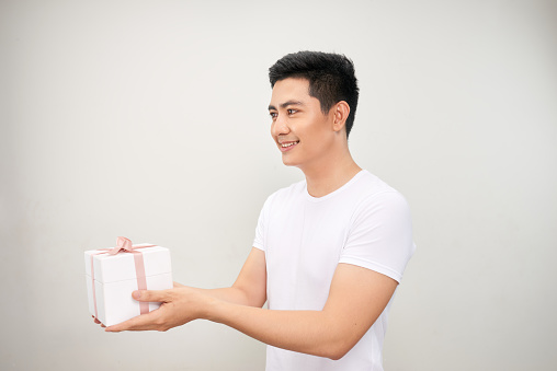 A happy handsome man presenting some gifts. Isolated on white background.