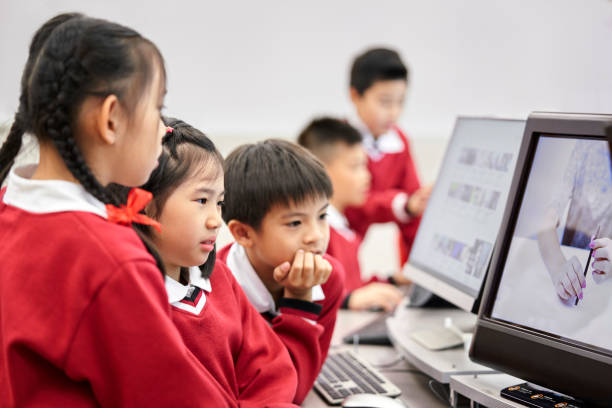 estudiantes enfocados viendo video en la computadora en el laboratorio - computer lab child internet development fotografías e imágenes de stock