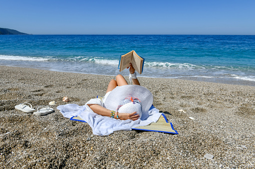 Woman studying book at the beach.
