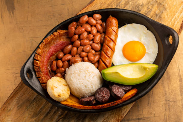 bandeja paisa, plat typique de la région d'antioquea en colombie. il se compose de chicharron (ventre de porc frit), boudin noir, saucisse, arepa, haricots, plantain frit, oeuf d'avocat, et le riz - bandeja paisa photos et images de collection