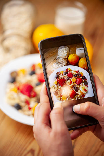 close-up of hands taking a picture of fruit and oats breakfast. - blueberry fruit berry berry fruit imagens e fotografias de stock