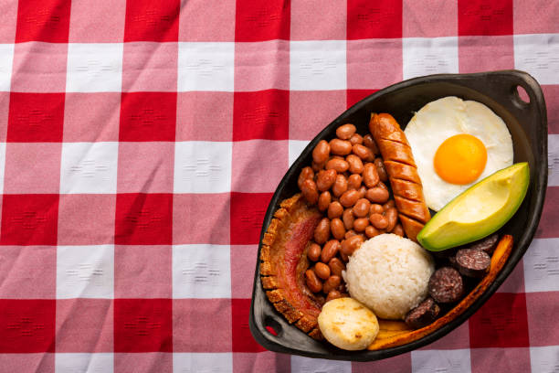 bandeja paisa, piatto tipico della regione di antioqueña in colombia. consiste di chicharrón (pancetta di maiale fritta), budino nero, salsiccia, arepa, fagioli, piantaggine fritta, uovo di avocado e riso - bandeja paisa foto e immagini stock