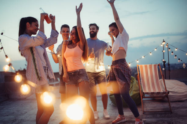 istock Happy friends with drinks toasting at rooftop party at night 1156693186
