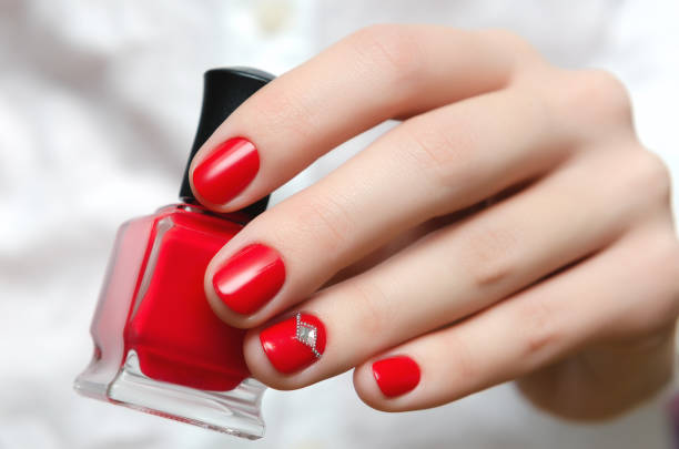 Female hand with red nail design holding nail polish bottle Female hand with red nail design holding nail polish bottle. red nail polish stock pictures, royalty-free photos & images