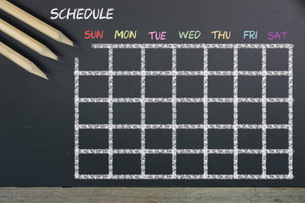 Schedule with grid time table on black chalkboard background stock photo