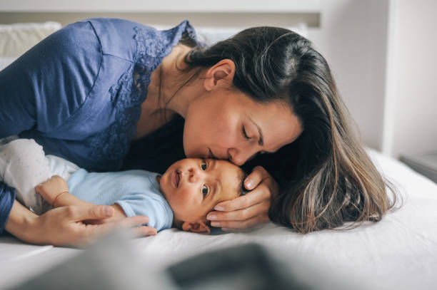 Mother kissing  her newborn baby boy stock photo