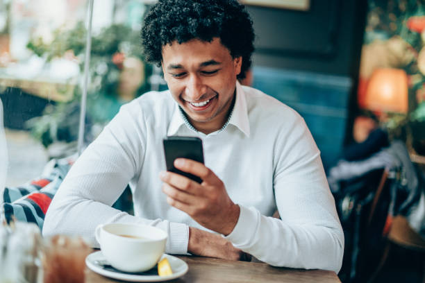 istock Afro-american man enjoying cup of tea and using smart phone 1156710427
