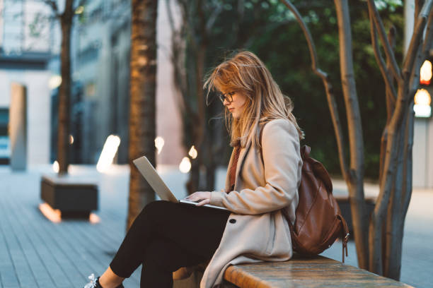 woman using laptop on a bench - school child education furniture imagens e fotografias de stock