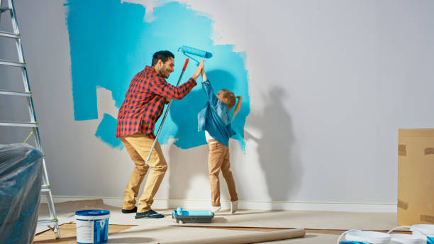 young father is showing how to paint walls to cute small daughter. they give high give to each other. rollers are covered in light blue paint. room renovations at home. - female house painter home decorator paintbrush imagens e fotografias de stock