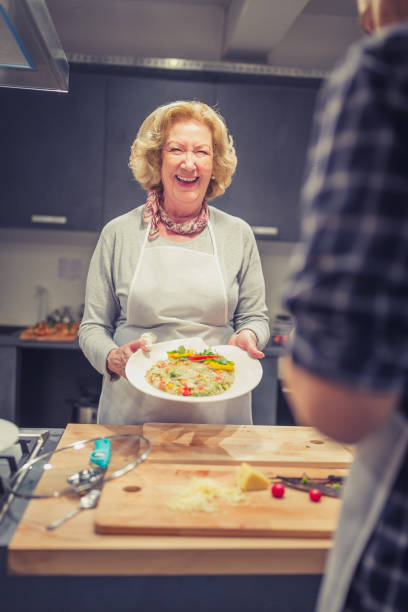 senhora sênior, um participante da classe de cozimento com risoto - vegan food cheerful vertical indoors - fotografias e filmes do acervo