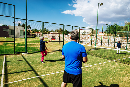 Senior Latino couple enjoying weekend with their grandchildren and family at home in summertime.