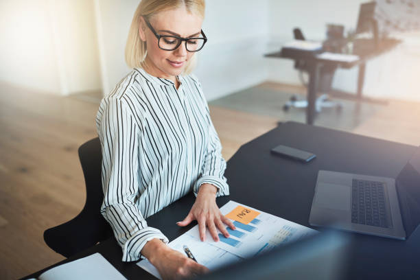 istock Smiling young businesswoman going over documents at her office desk 1156716471