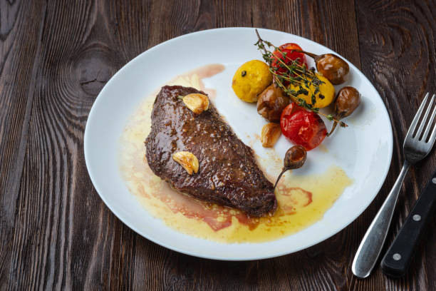 istock Rib-eye steak with baked vegetables resting on a white plate 1156716575