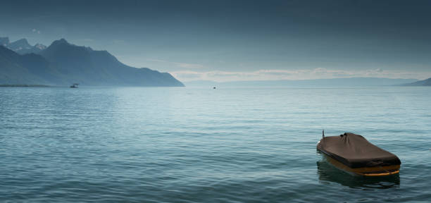 A beautiful view of Lake Geneva and surrounding mountains on a summer day with a single boat in the foreground