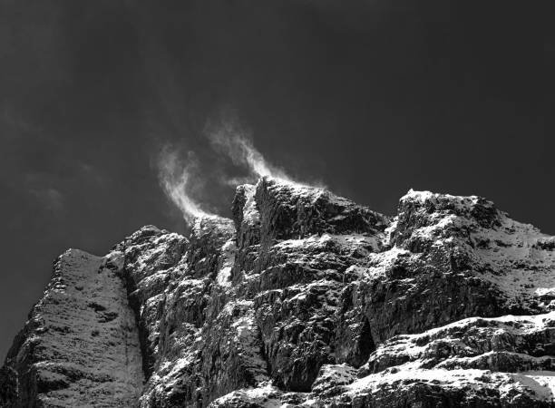 The snow on top of a mountain in Scotland is blown up by a strong gust of wind