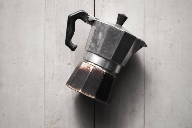 Old Italian moka pot lay on gray table Old Italian moka pot lay on gray wooden table. It is a old stove-top coffee maker that brews coffee by passing boiling water pressurized by steam through ground coffee moka stock pictures, royalty-free photos & images