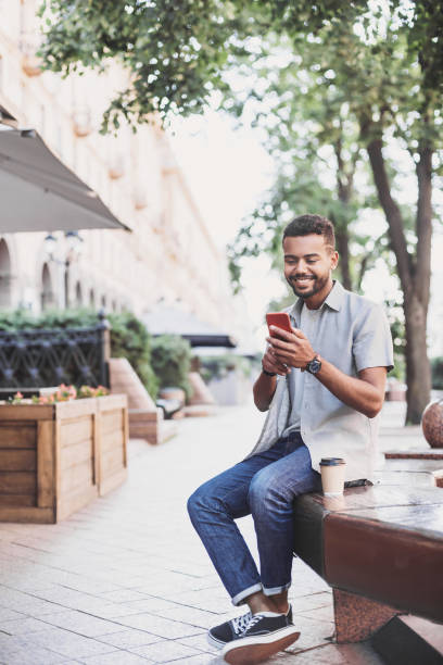 Cheerful young man using smart phone in a city