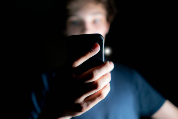 young attractive man use mobile phone late at night in a dark room b stock photo