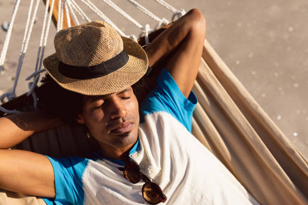 istock Man with hat sleeping in a hammock on the beach 1156727927
