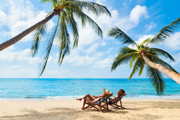 paar entspannen am strand und genießen schönes meer auf der tropischen insel - strandurlaub stock-fotos und bilder