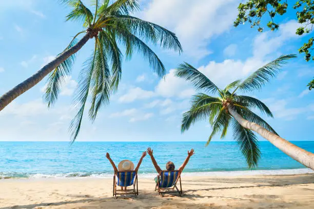 Photo of Happy couple with arms up relax on the beach enjoy beautiful sea on the tropical island