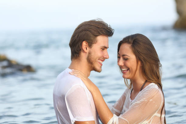istock Happy couple laughing bathing on the beach 1156732907