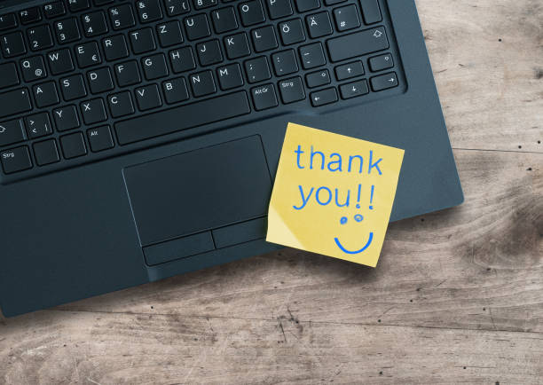 thank you written on sticky note on laptop computer stock photo