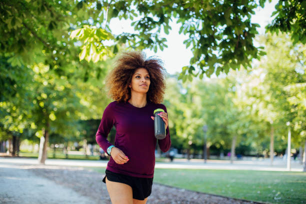 istock Woman with water bottle jogging 1156733675