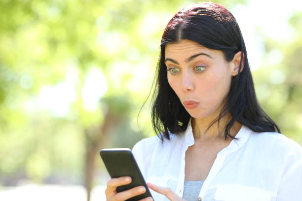 istock Perplexed woman reading phone content in a park 1156733730