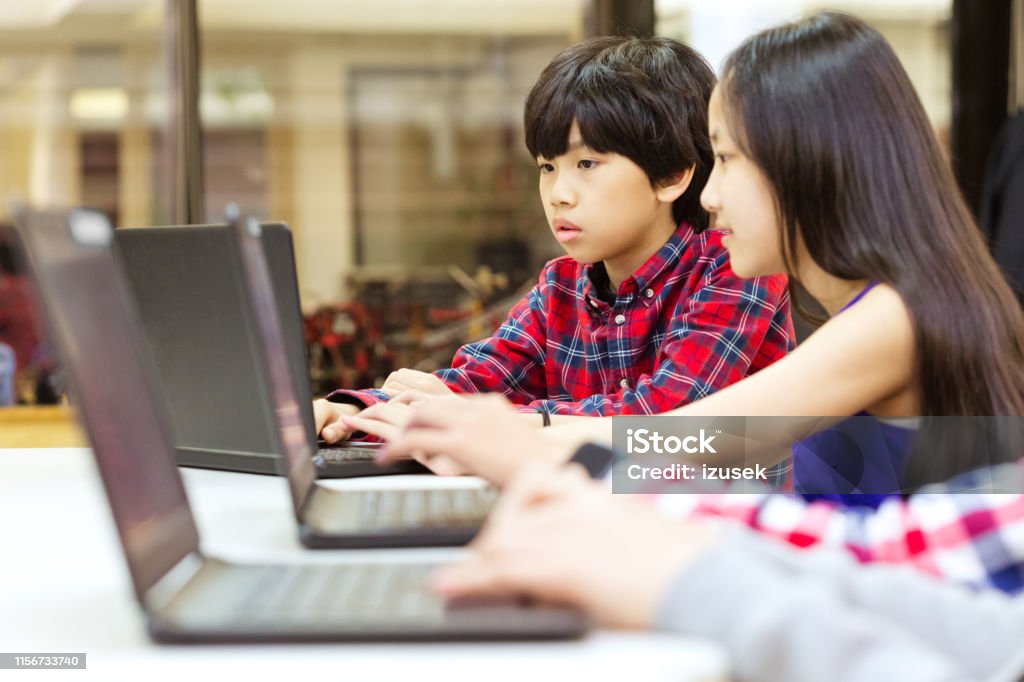 Students using laptop during coding lecture Students using laptop at desk during coding lecture. Girl and boy sharing technology in classroom. They are in programming school. 10-11 Years Stock Photo Students using laptop during coding lecture Students using laptop at desk during coding lecture. Girl and boy sharing technology in classroom. They are in programming school. 10-11 Years Stock Photo