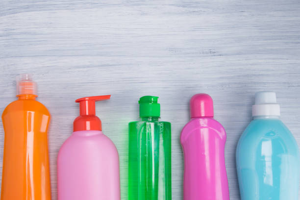 istock on a light gray background, multi-colored bottles with liquids for cleaning surfaces, washing dishes and washing clothes, arranged in a row, there is an inscription above 1156736156
