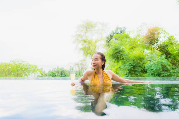 istock Smiling Young Woman In Infinity Pool Against Trees 1156742159