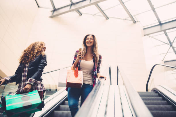 Young women moving down with escalator in the shopping mall