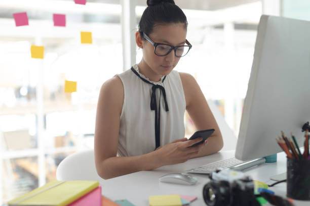 istock Female graphic designer using mobile phone at desk in a modern office 1156743292