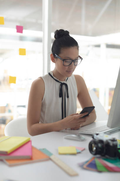 istock Female graphic designer using mobile phone at desk in a modern office 1156743331