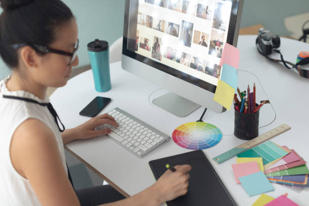 istock Female graphic designer using graphic tablet at desk in a modern office 1156744975