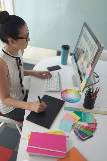 istock Female graphic designer using graphic tablet at desk in a modern office 1156745611