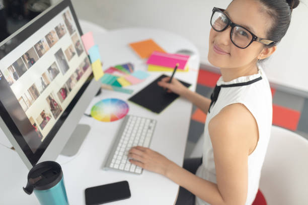 istock Female graphic designer using graphic tablet at desk in a modern office 1156745761