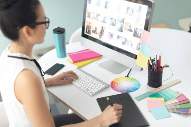 istock Female graphic designer using graphic tablet at desk in a modern office 1156745786