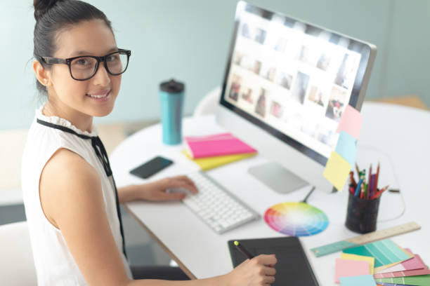 istock Female graphic designer using graphic tablet at desk in a modern office 1156745856