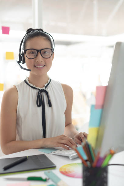istock Female graphic designer in headset looking at camera while working at desk in a modern office 1156747068