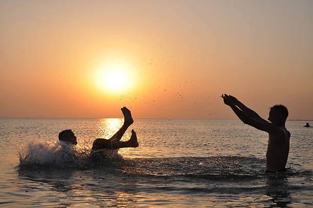 istock Two people jumping in sea at sunset. 115674767