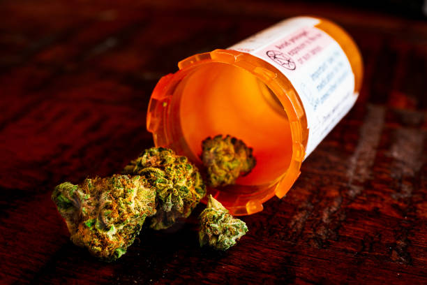ピルボトルからこぼれる乾燥大麻芽 - medical marijuana ストックフォトと画像