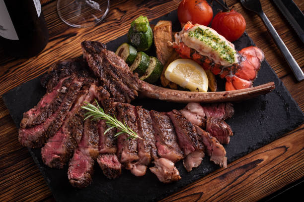 トマホークリブアイステーキとロブスターテールを持つサーフと芝 - rib eye steak steak beef prepared potato ストックフォトと画像